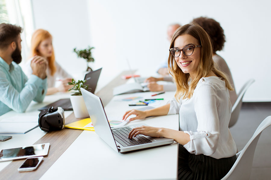 chicas sentadas en una mesa de trabajo una de ellas mirando a la cámara